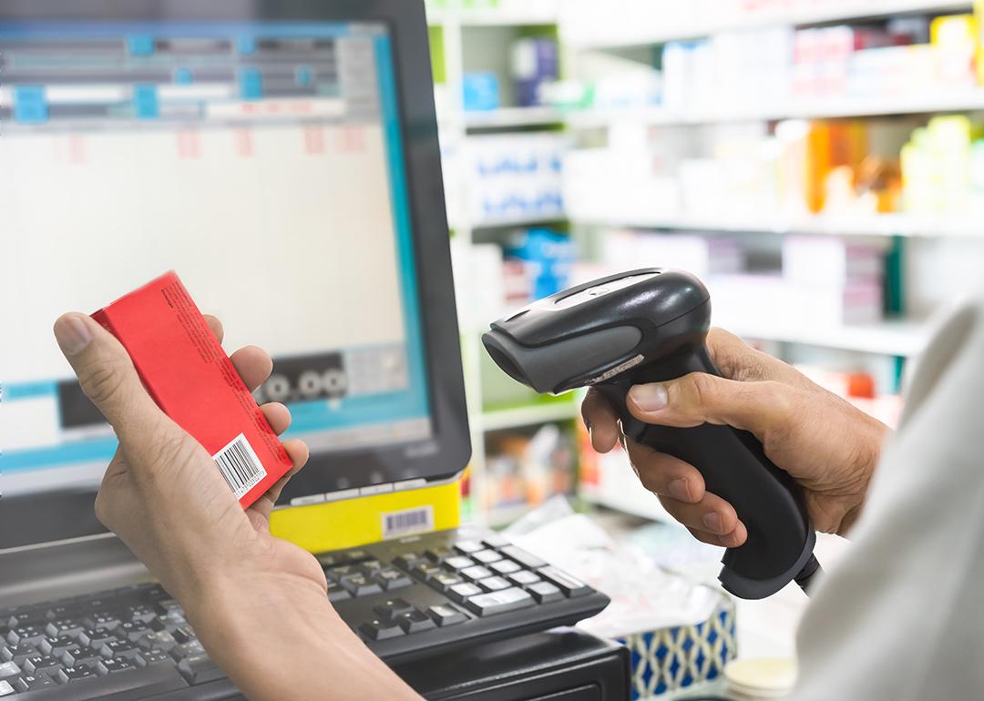 Pharmacist scanning price on a box of medicine.