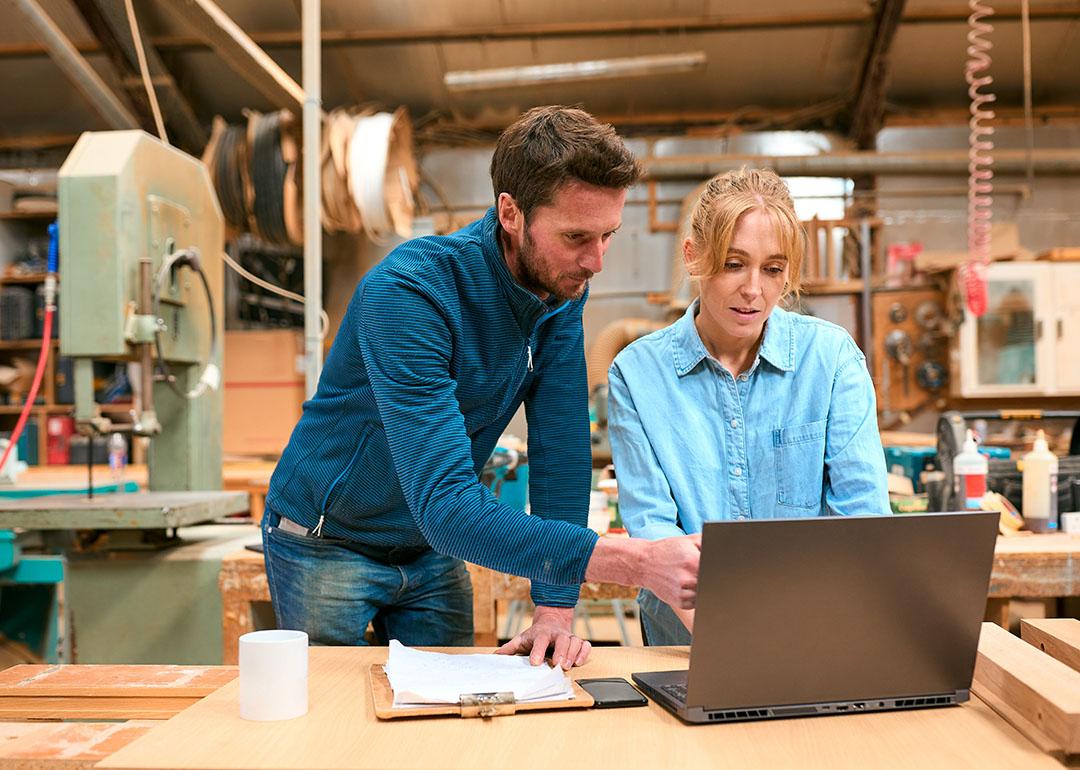 A pair of woodwork business owners reviewing reports in a laptop.