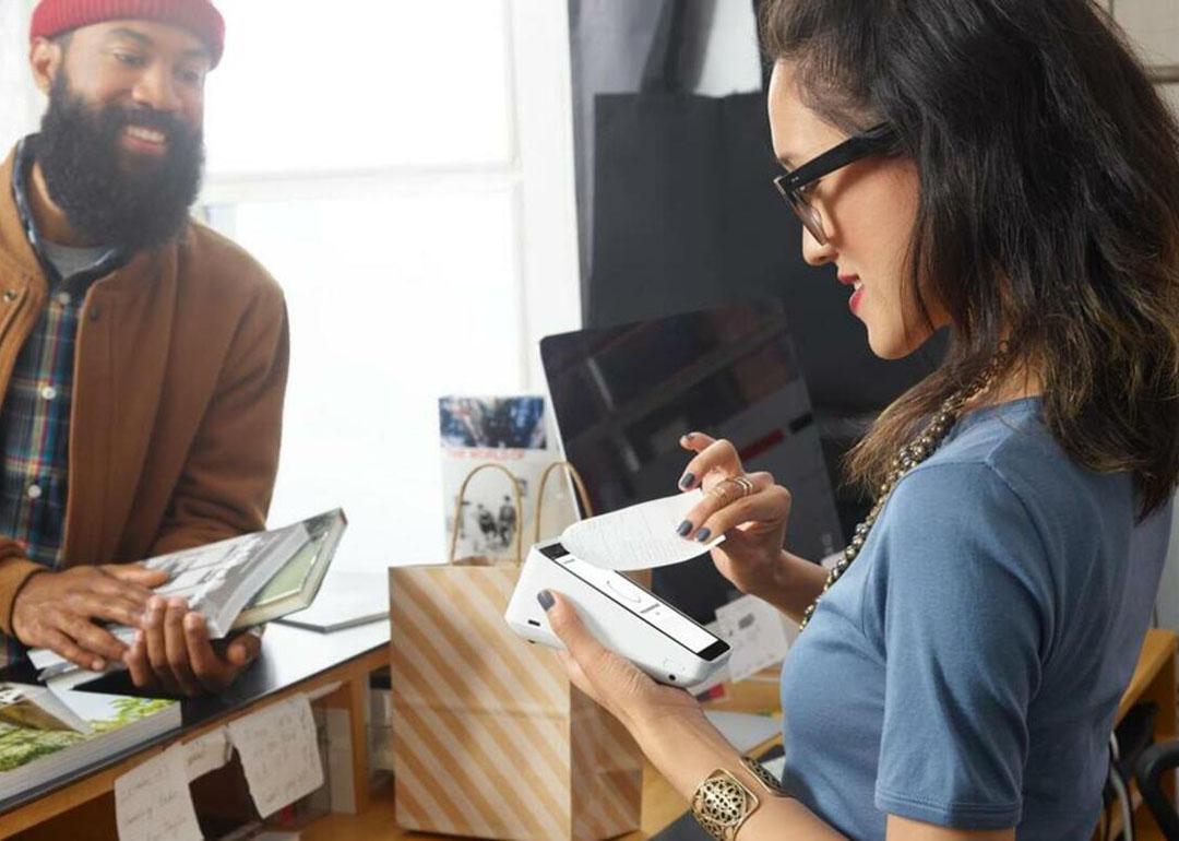 A sales staff at a book shop printing the receipt from a handheld POS to give to the customer.