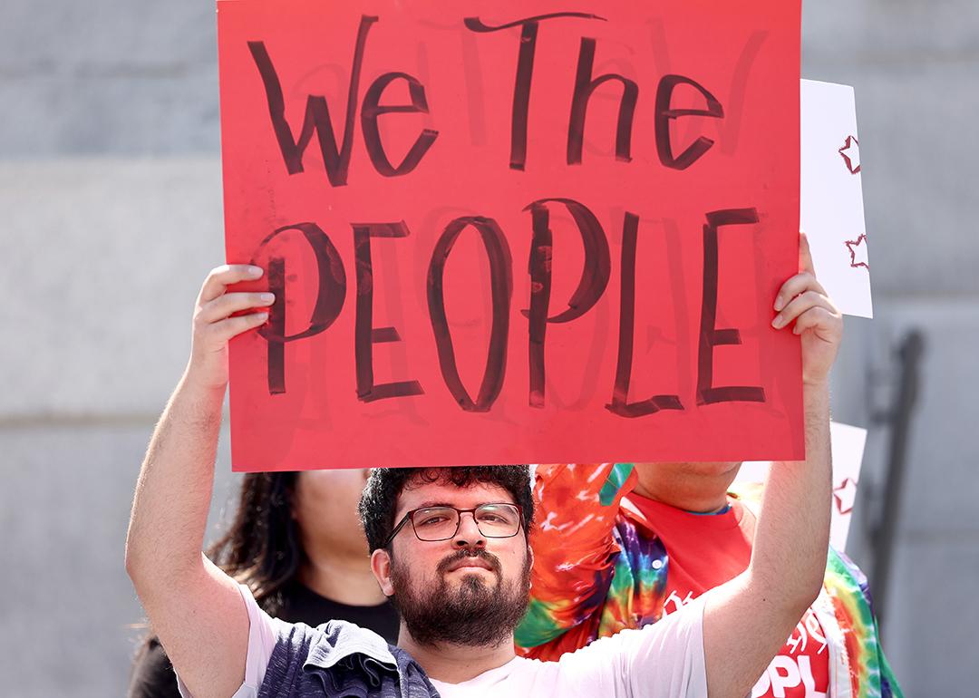Demonstrators hold signs during the We The People March in Los Angeles, California.