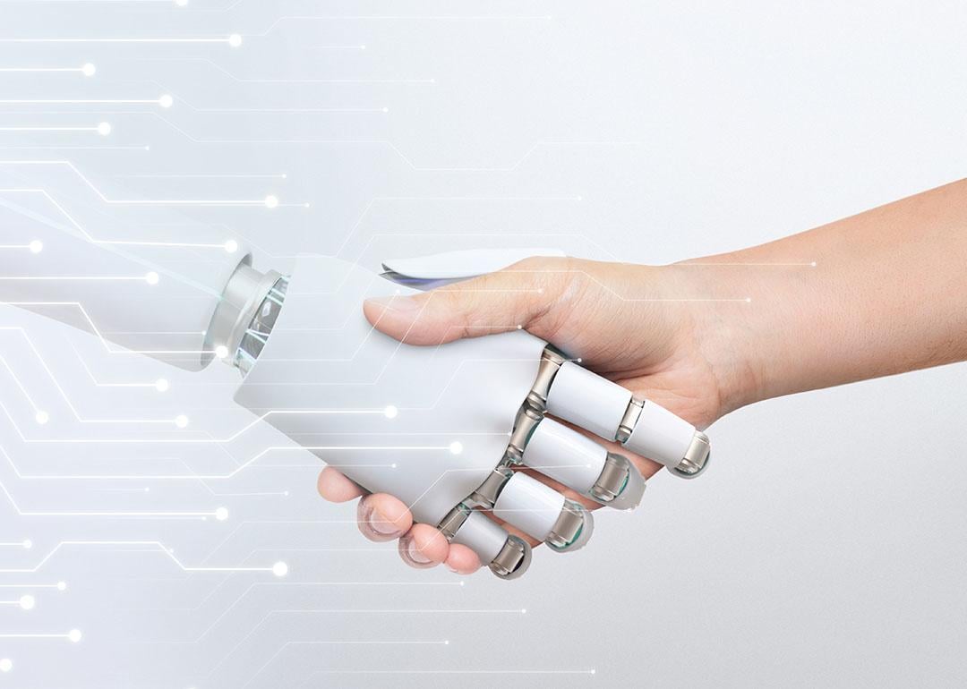 Human hand shaking robot hand, symbolizing human-robot collaboration and technology.