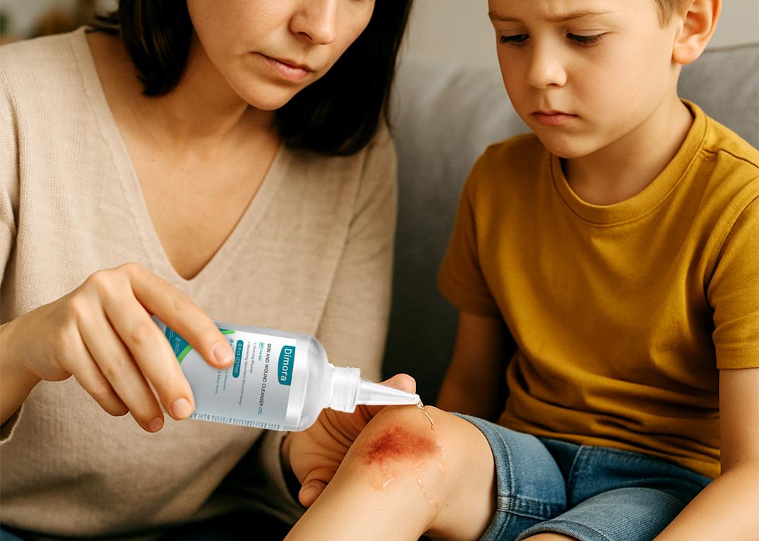 A mother tends to her son's knee wound by with drops of a Dimora wound cleanser.