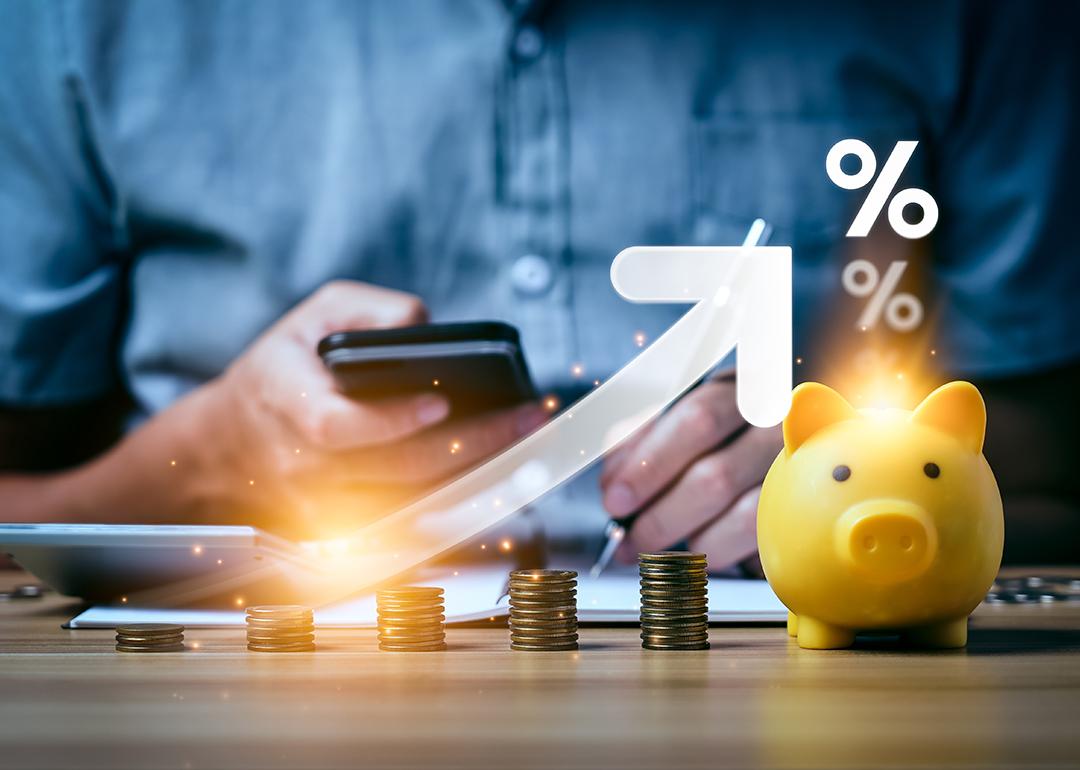 A business professional calculating and saving finances illustrated with increasing interest rates graphics.
