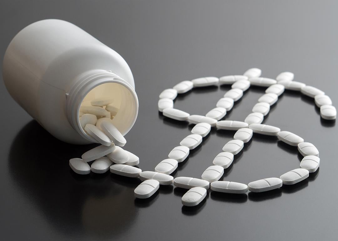 Pills from a bottle forming a dollar sign as a concept of rising medicine costs.