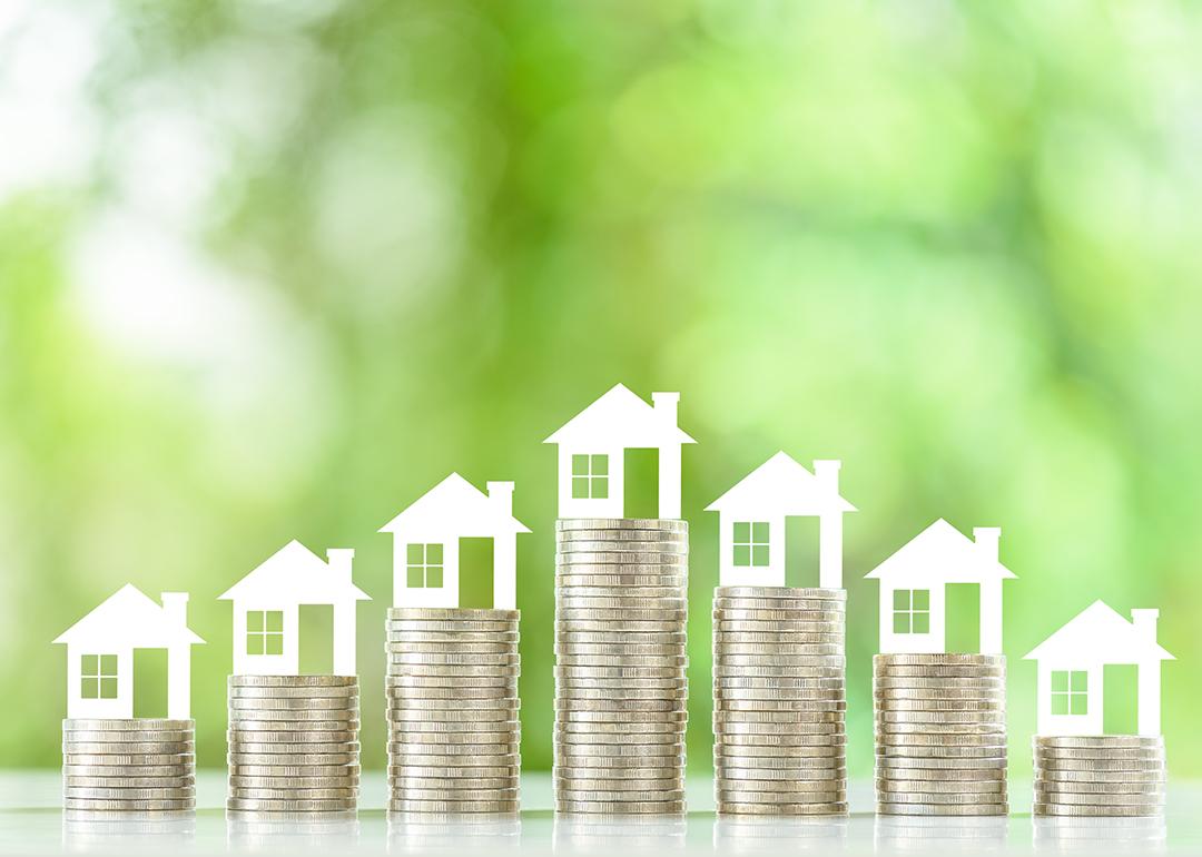Tiny figures of residential houses atop coin stacks.