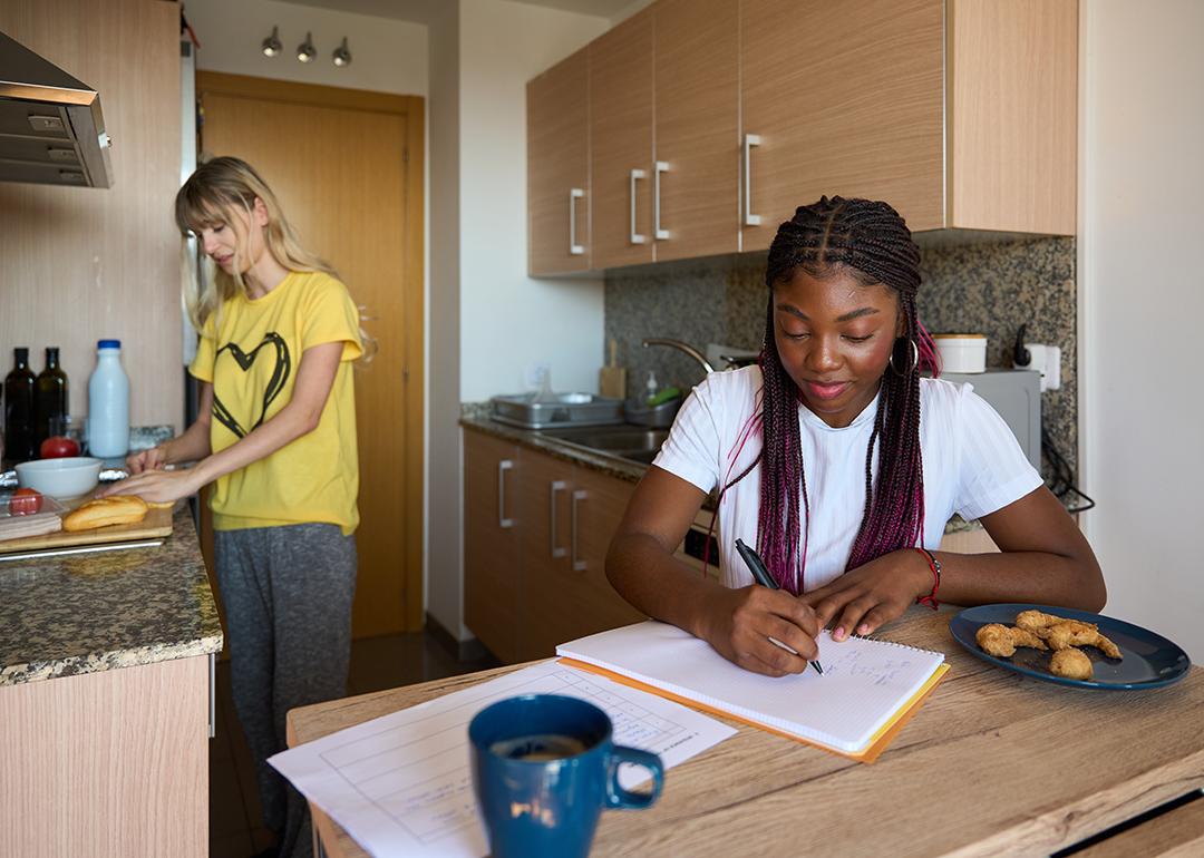 Two young adult women who are roommates in a small apartment.