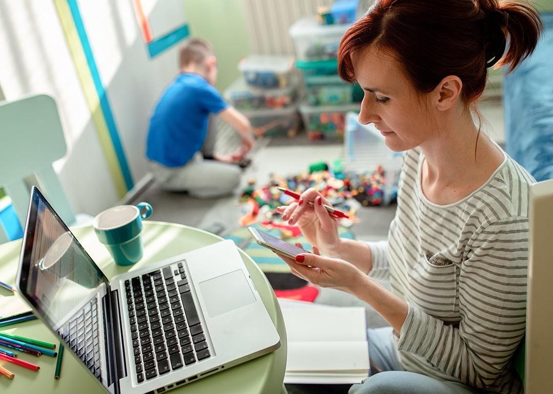 Mother working from home with a laptop and phone.