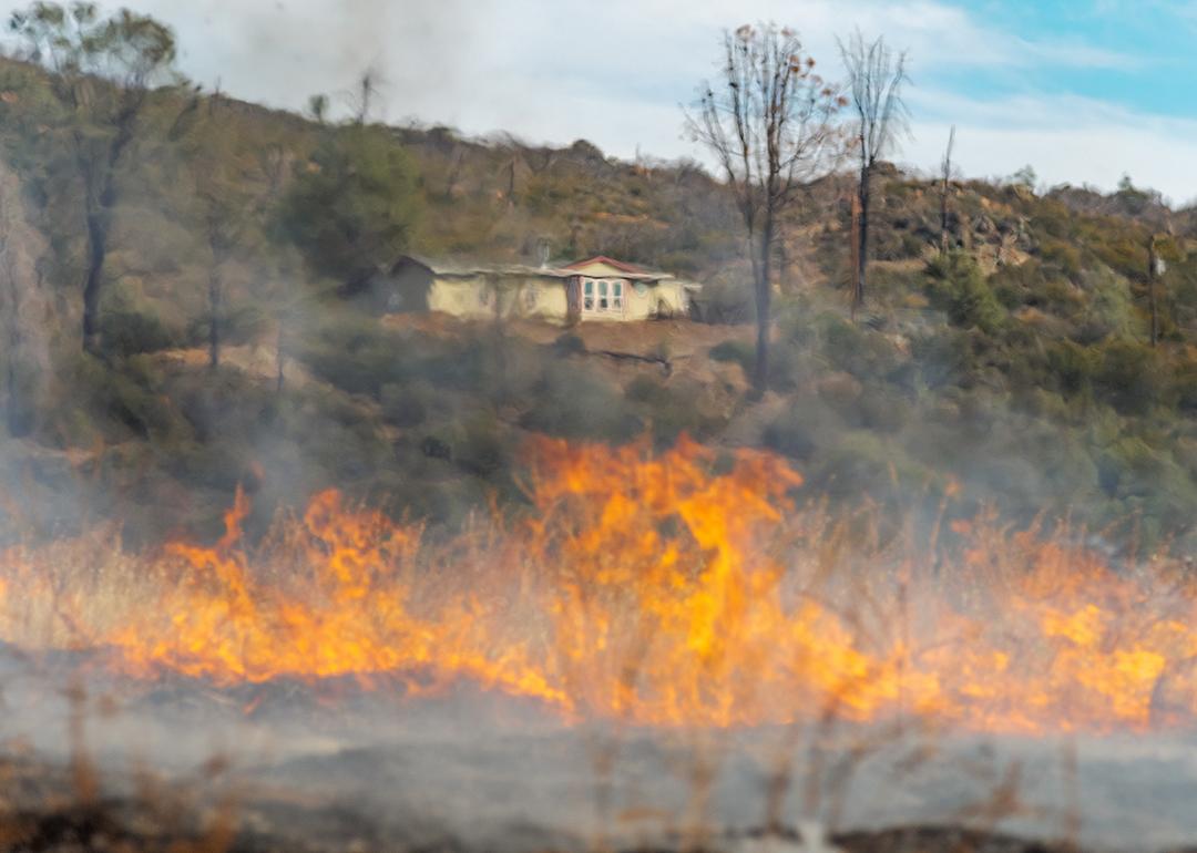 A wildfire blurs the view of a home from a distance.