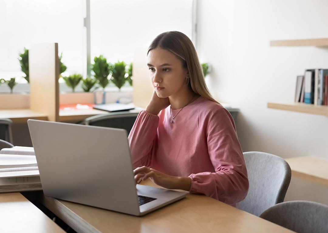 Young college student using a laptop to browse through finances.