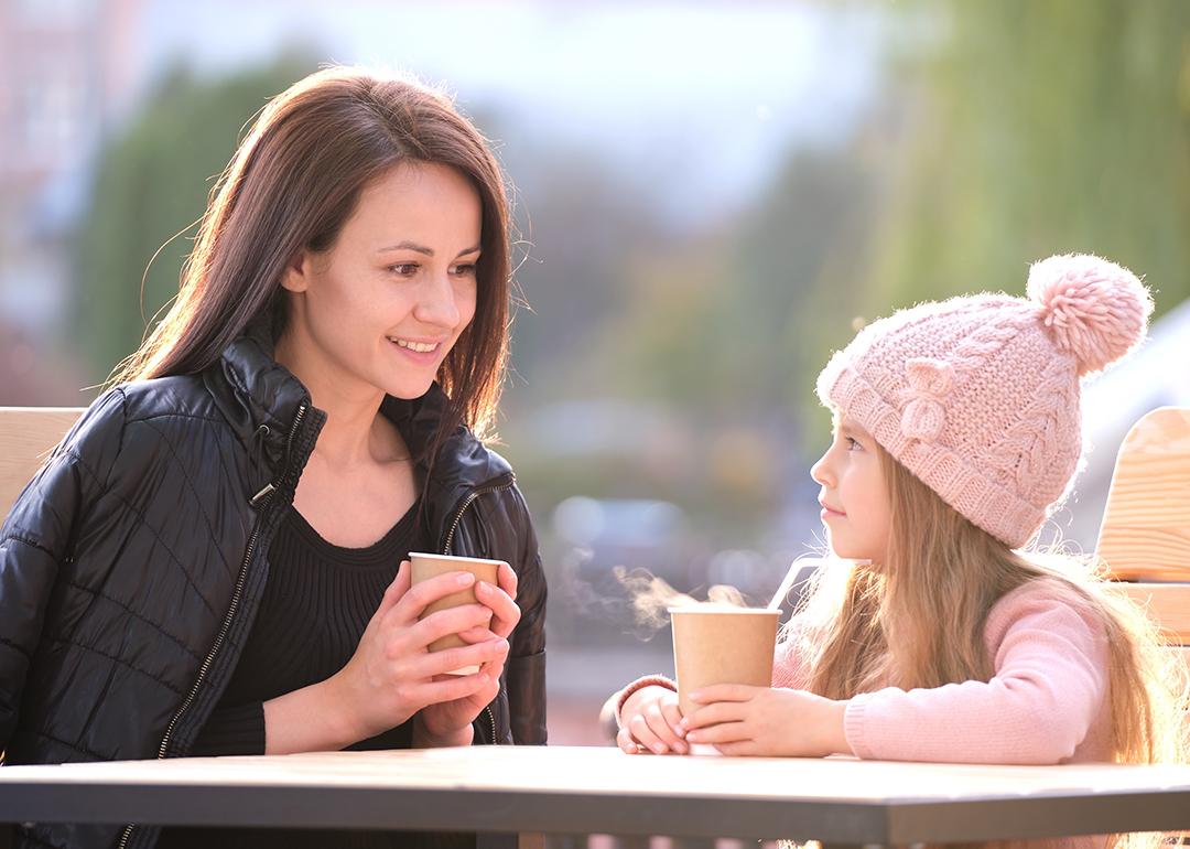 A mother having a good time with her young daughter in a cafe outdoors.