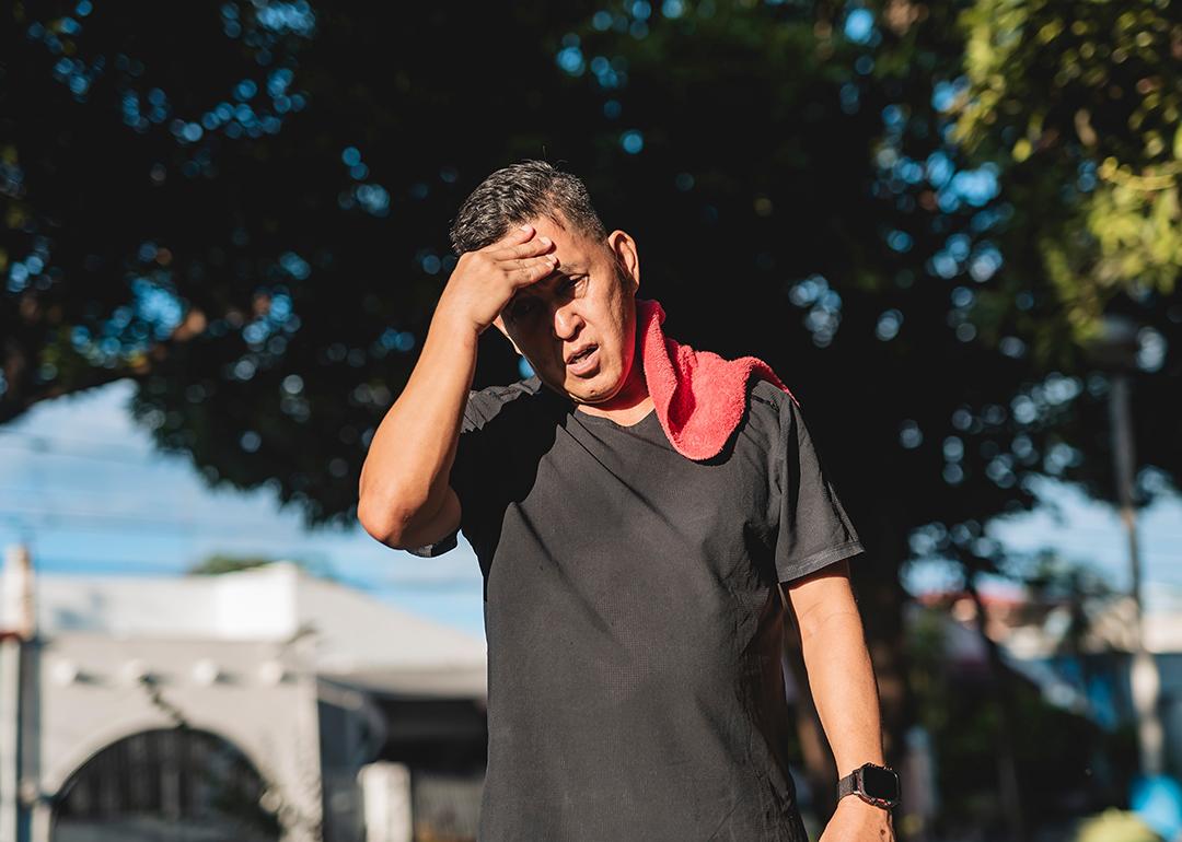 A middle-aged Southeast Asian man walking on a hot day after exercise.