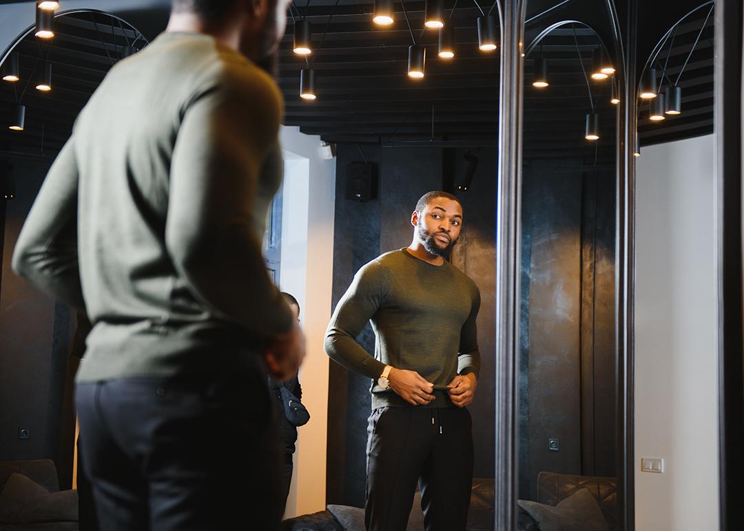 A stylish man looking in front of the mirror to check his outfit.