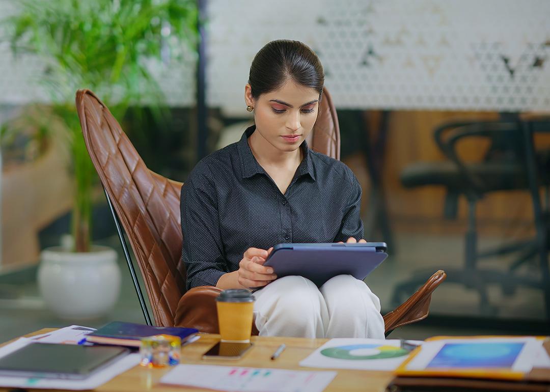 Young businesswoman in workplace using a tablet to browse information online.