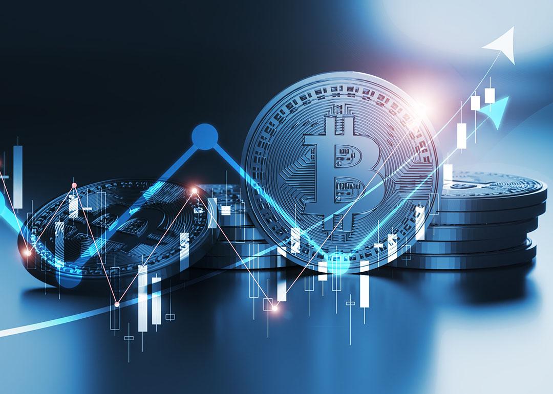 Concept of bitcoin value fluctuations illustrated by image of chart trending prices going up and down overlaid on a bitcoin illustration.