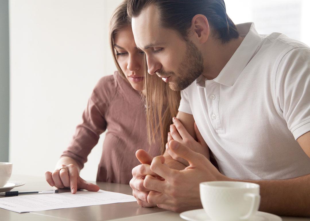Two people looking over paperwork carefully, lit by window light during the daytime.