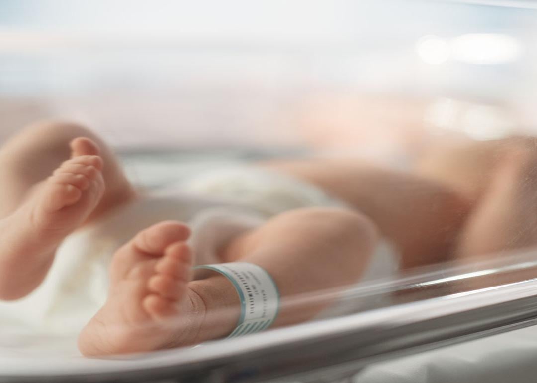 Newborn baby lying in bassinet in hospital with toes and feet in focus.