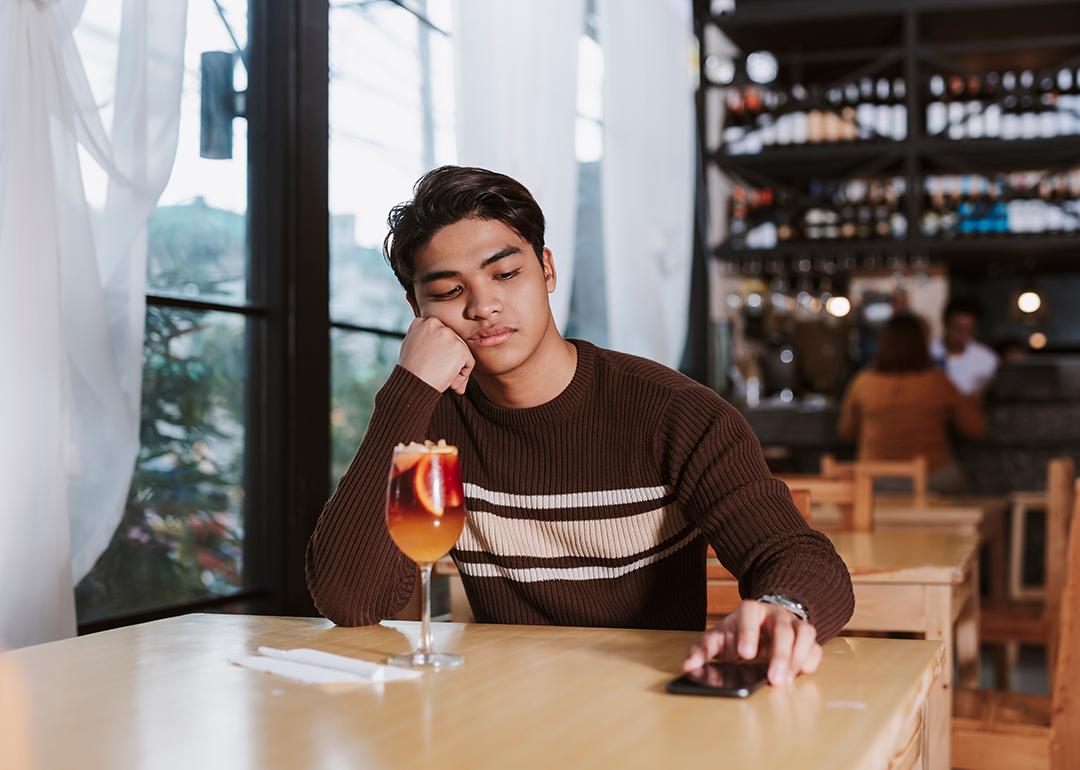 Young man who was ghosted by his date sits alone disappointed in a restaurant.