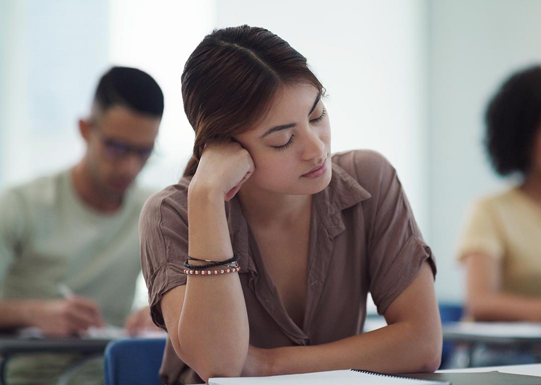 Young female college student feeling burned out in a classroom.