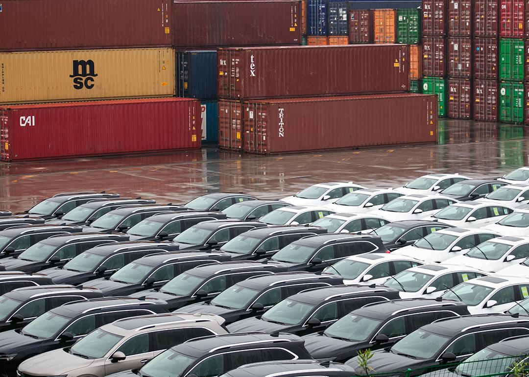 Rows of imported cars lined up across shipping containers.