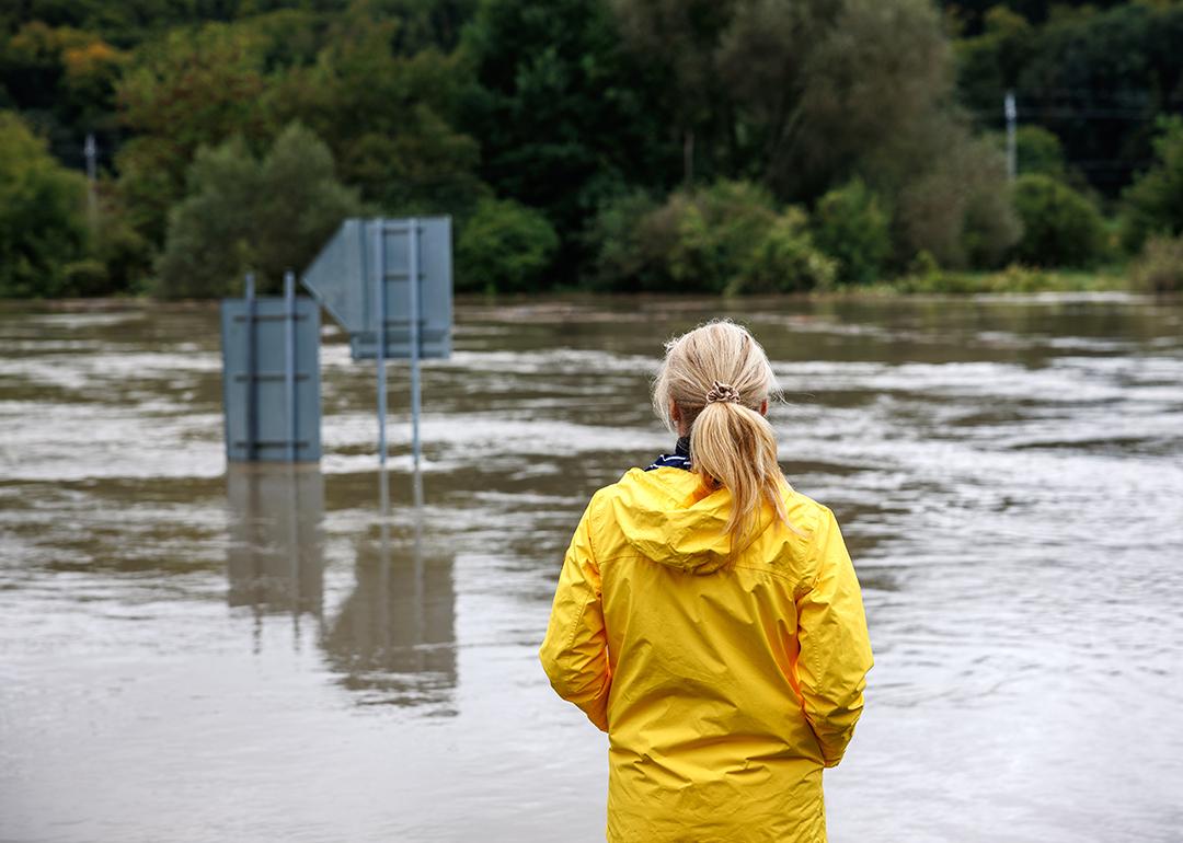A woman in a raincoat looking over a huge flood.