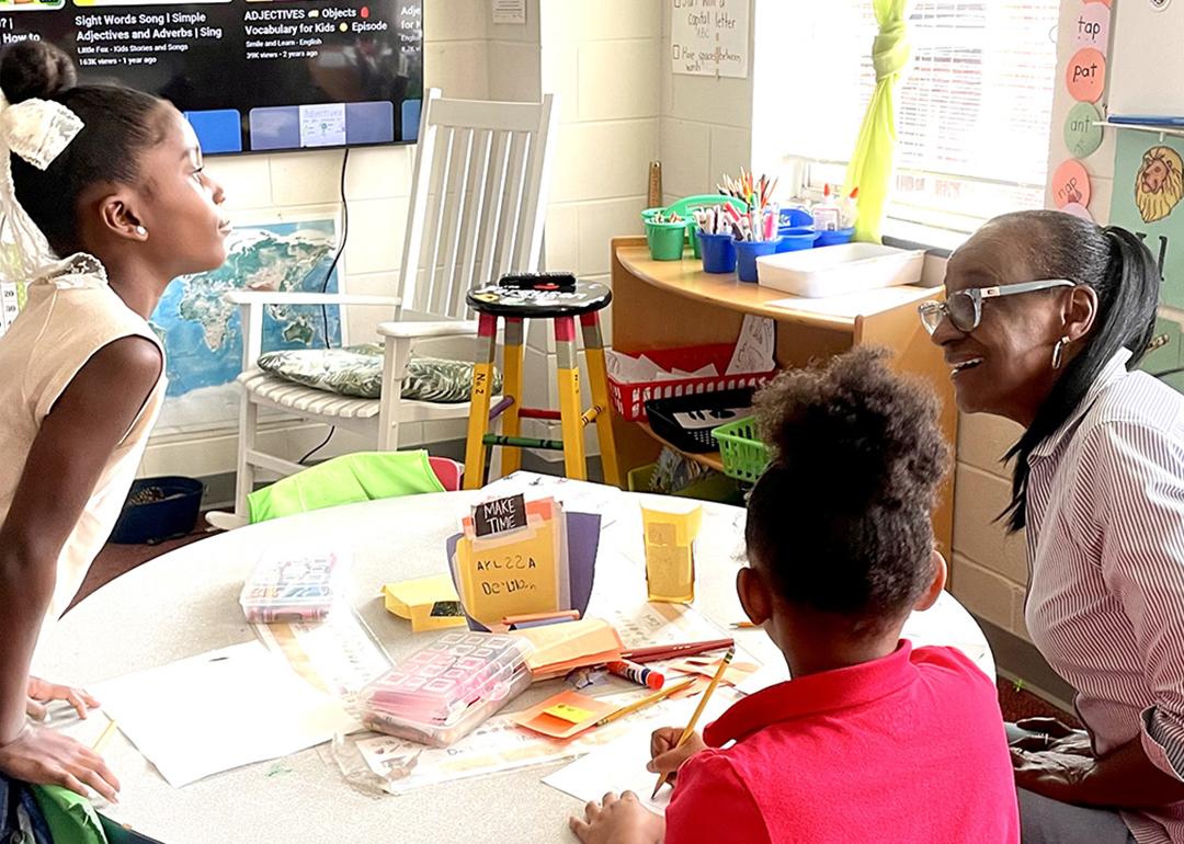 Volunteer Gae Bryant, right, works on a drawing exercise with two students in the K-2 class at The Ferguson School, a microschool that meets in an Atlanta-area church.
