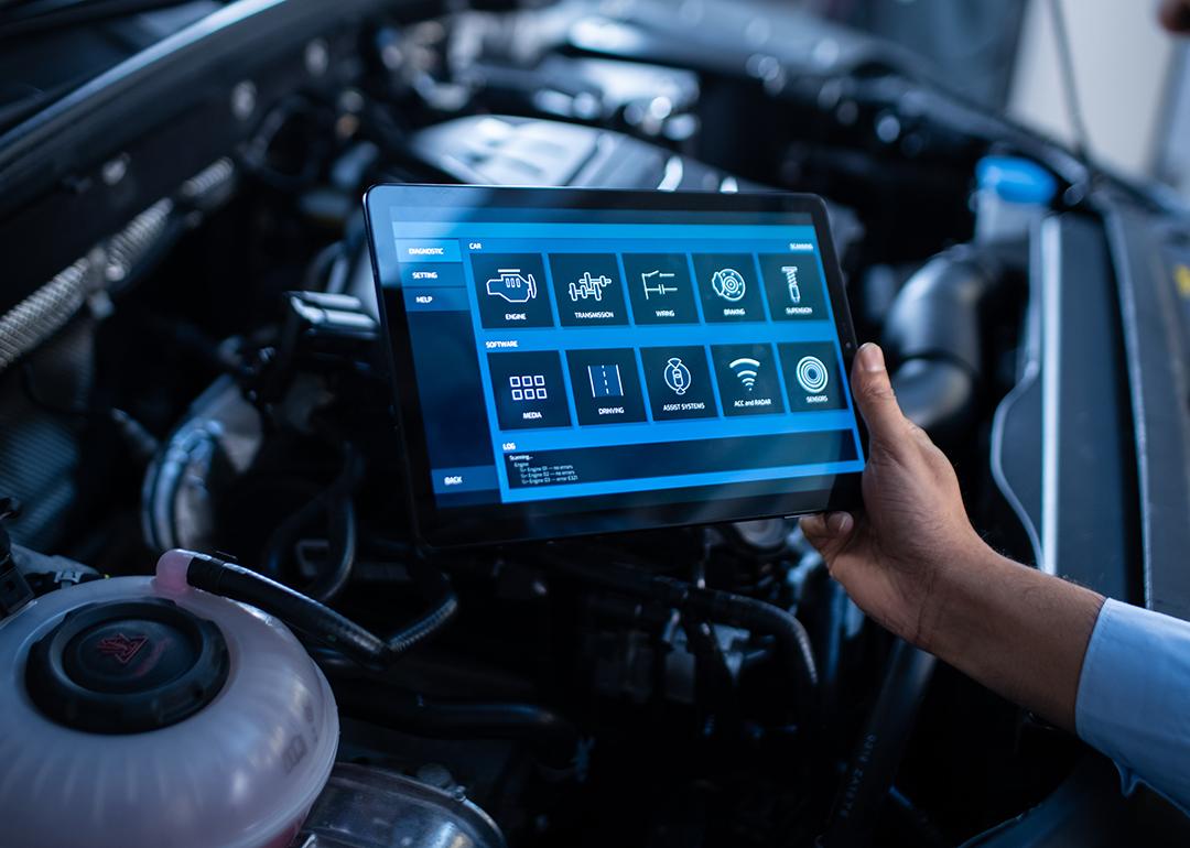 A mechanic using a tablet to configure a car's issue and repair.