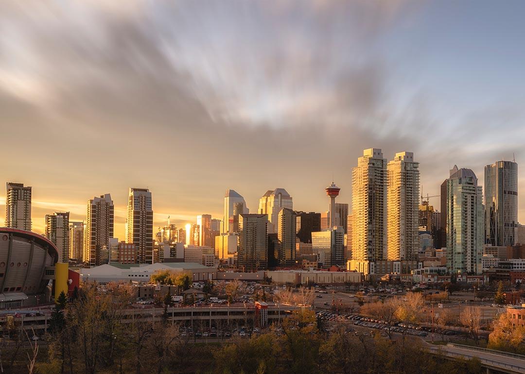 Skyline of Calgary during sunset with golden light reflecting off skyscrapers.