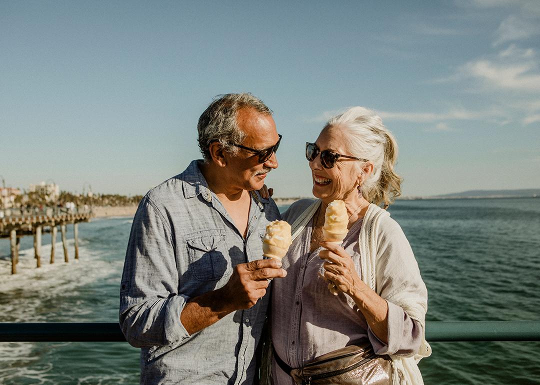 An older couple eating ice cream while standing on the Santa Monica pier.