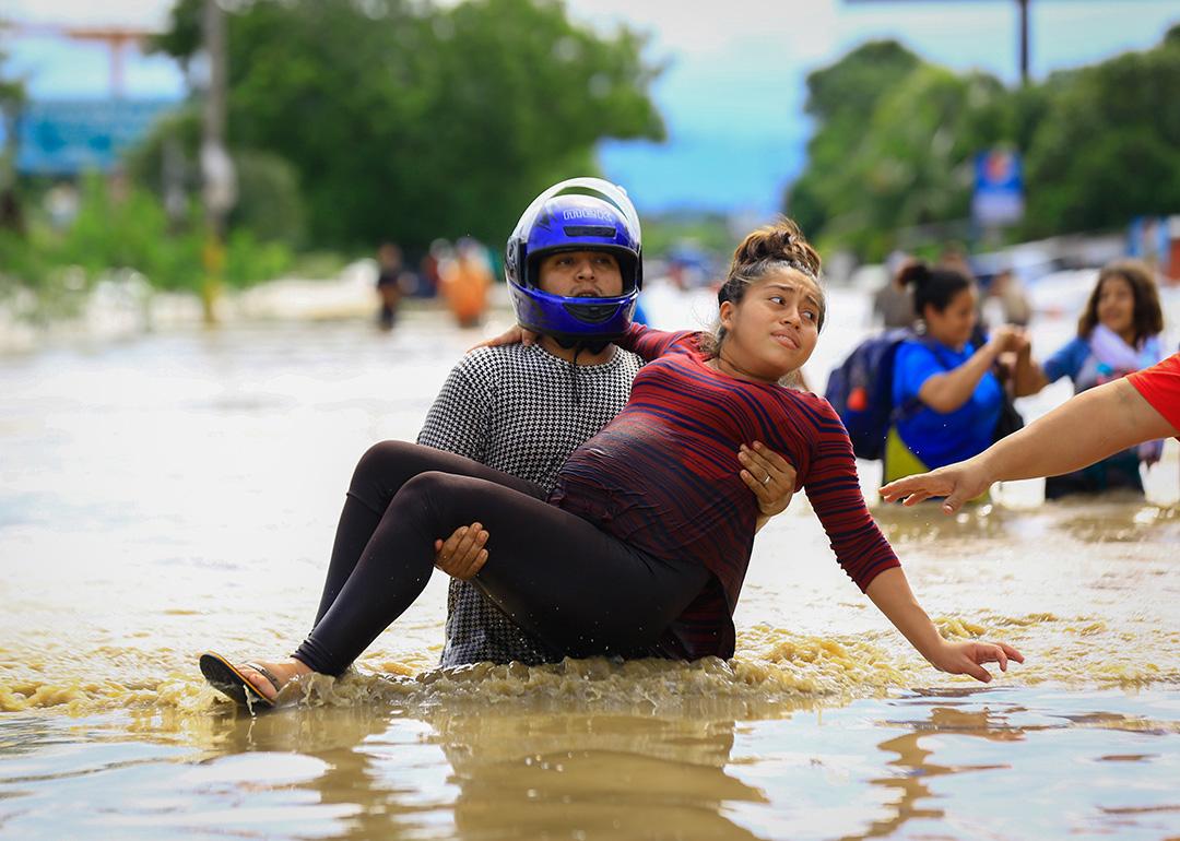 A man carries a pregnant woman through a flooded road in La Lima, Honduras after the low pressure system "Eta" caused heavy rainfall throughout the region.