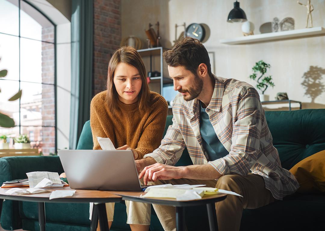 Young couple organizing bills with a laptop.