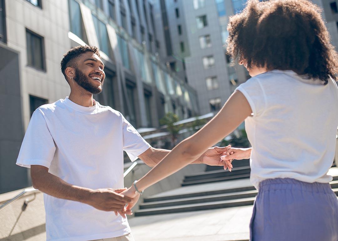 Young Black couple facing each other holding hands and playing around, dancing.