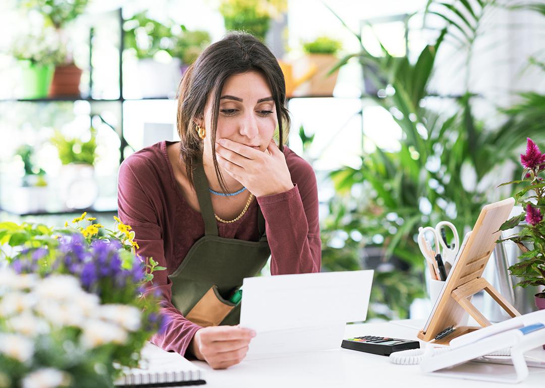 A flower shop owner carefully reviewing business documents while at the store.