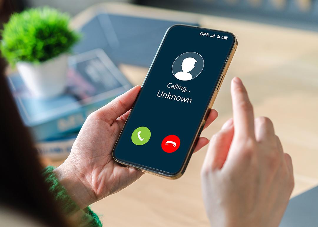Woman contemplating to answer an unknown call on her mobile phone.