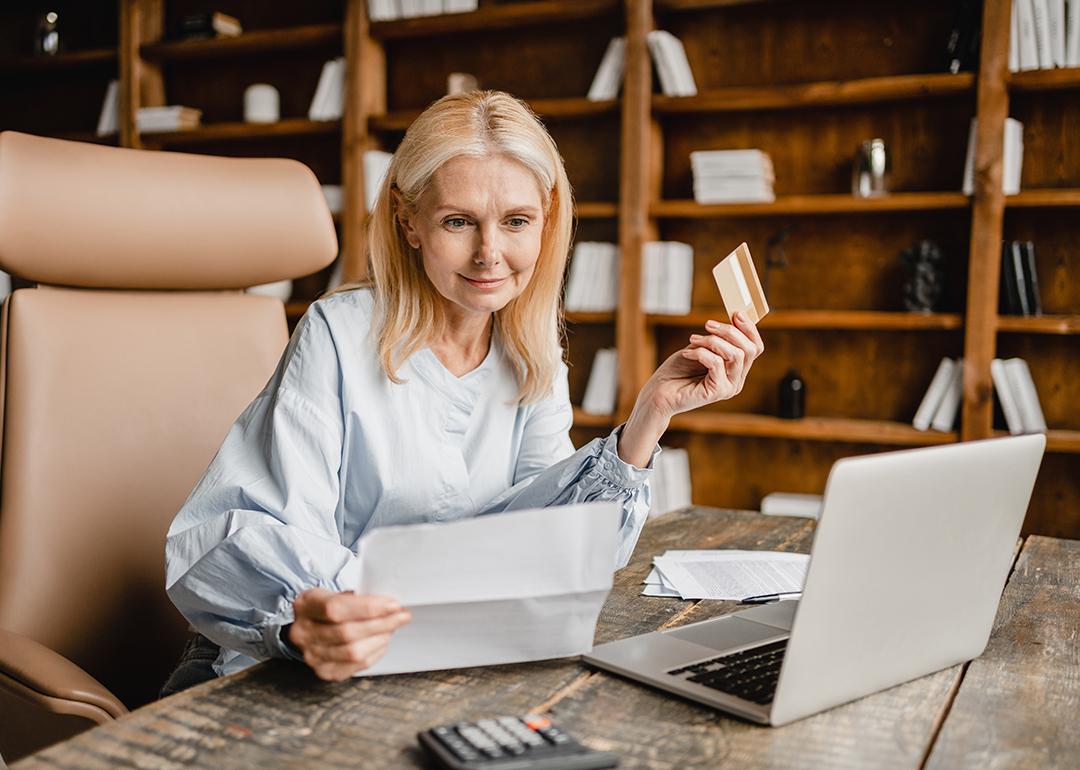 Senior businesswoman using company card to pay a bill online.