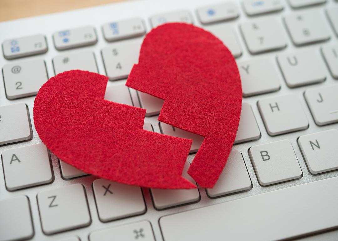 A red broken heart cutout on top of a white keyboard.