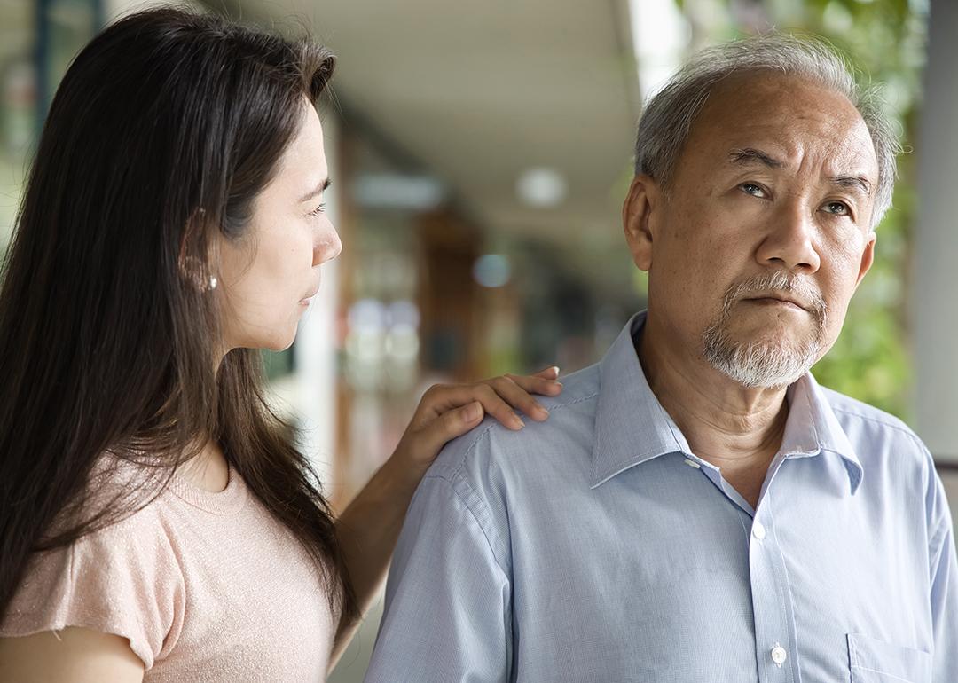 A middle-aged daughter looking worried at his elderly father who has dementia.