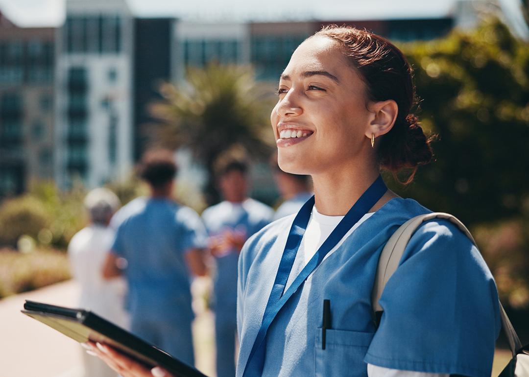 A nursing student happily using a tablet inside campus.
