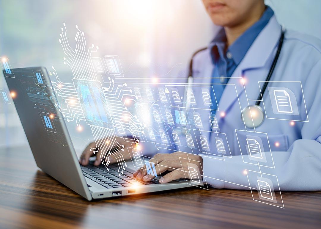 Concept of doctors using AI illustrated with medical professional with white coat and stethoscope using laptop computer with AI icons and symbols overlaid.