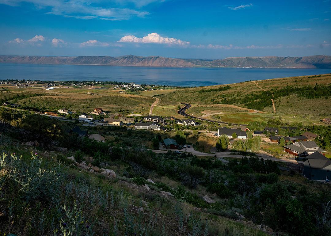 A view of Bear Lake with mountains in the distance with hills and homes in the foreground from July 2024.