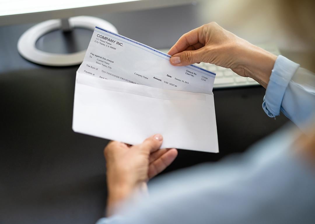 Worker pulling out a paycheck from its envelope.