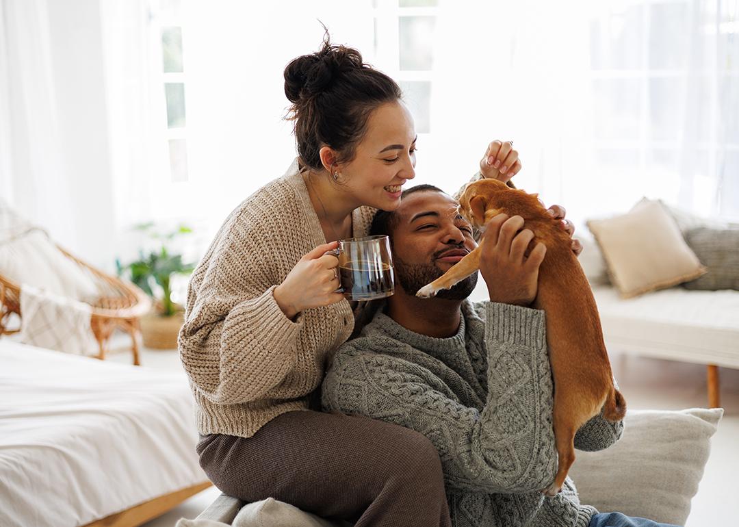 Happy couple at home playing with their dog.