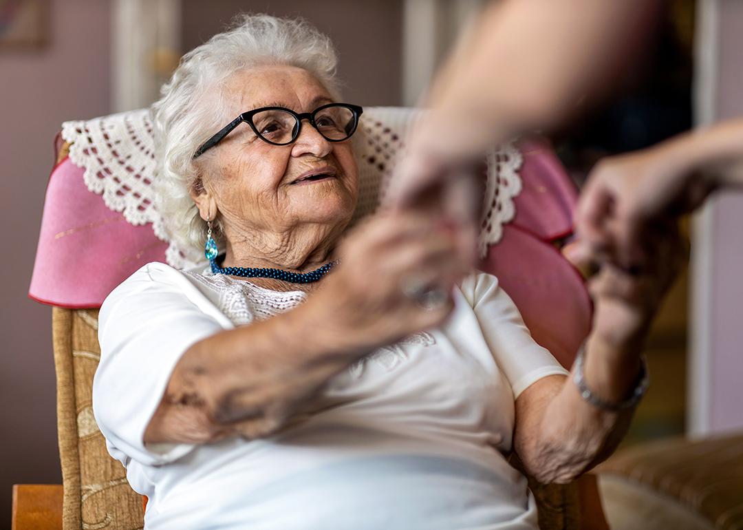 An elderly woman being assisted by her caregiver to stand up.