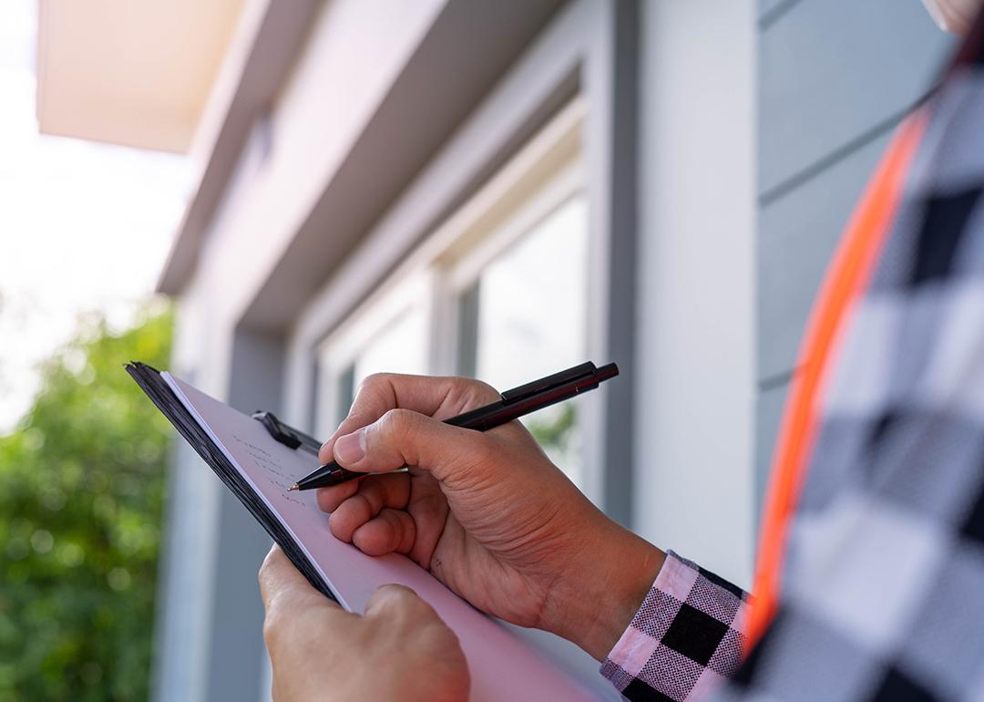 An inspector checking off a list while looking at a property.