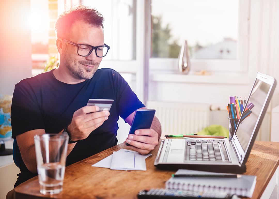 Man in his home office using a credit card for an online transaction.