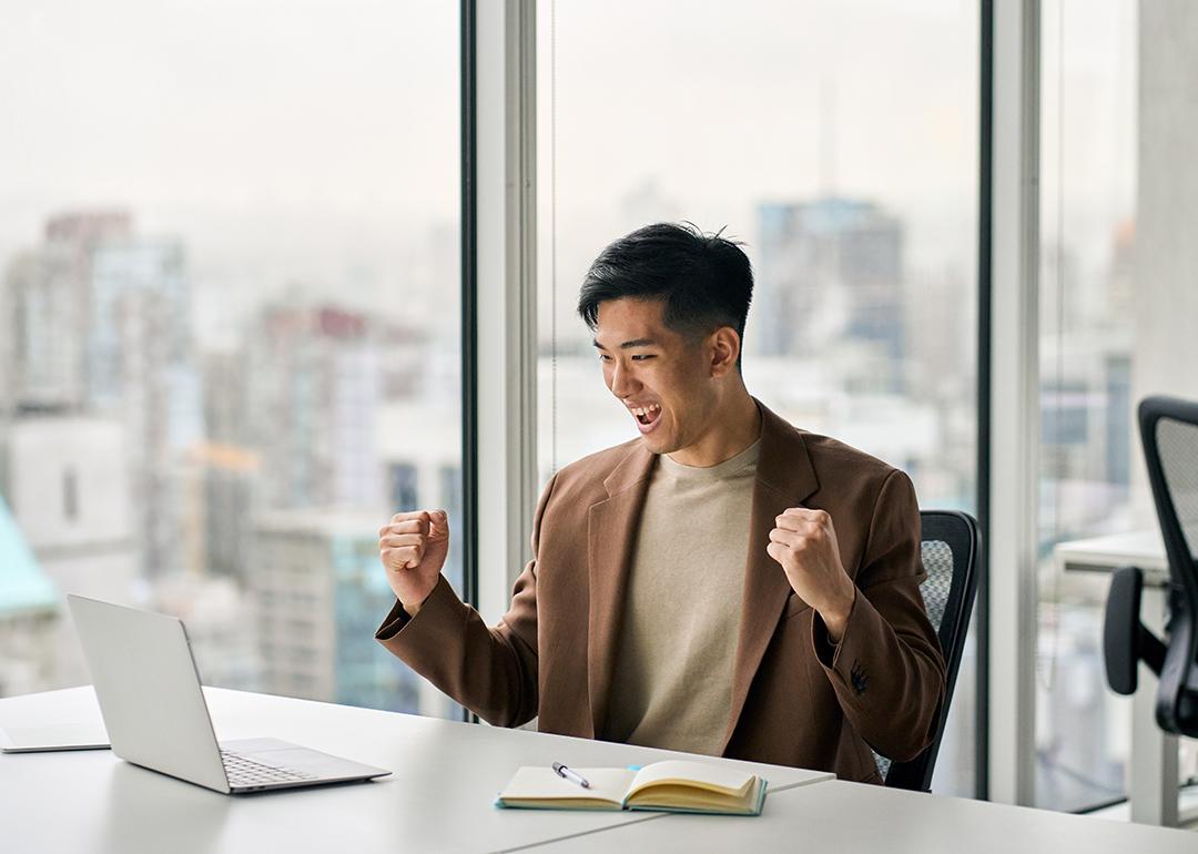 Businessman celebrating a success at work in front of a laptop.