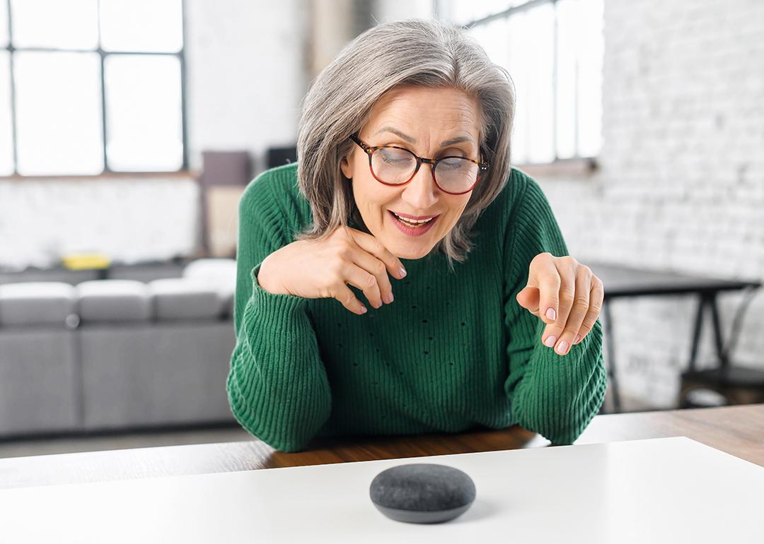 Retired woman using a voice command on a smart speaker with AI at home.