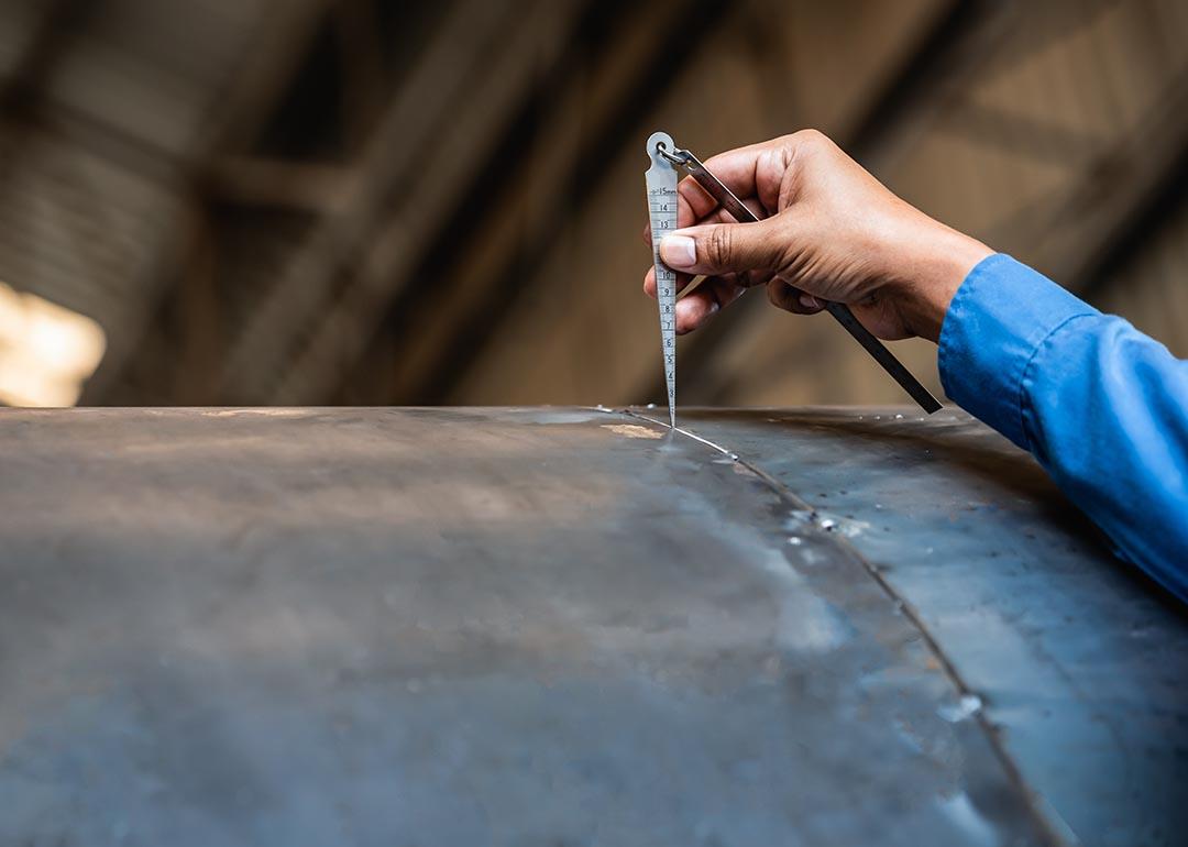 NDT inspector using welding gauge to inspect joint preparation or groove weld on a structure.