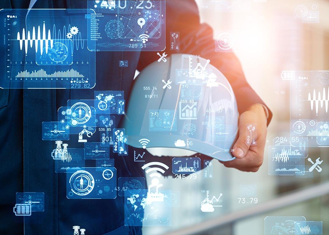 White hard hat held in the crook of a person's arm with technology icons superimposed symbolizing AI advance and sautomation of manufacturing processes using computers and electronics.