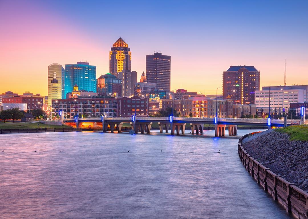 Cityscape image of Des Moines skyline, Iowa bridge over water with summer sunset.