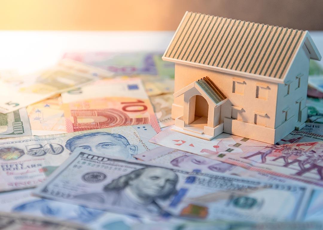 House model on various of international banknotes on the table. 